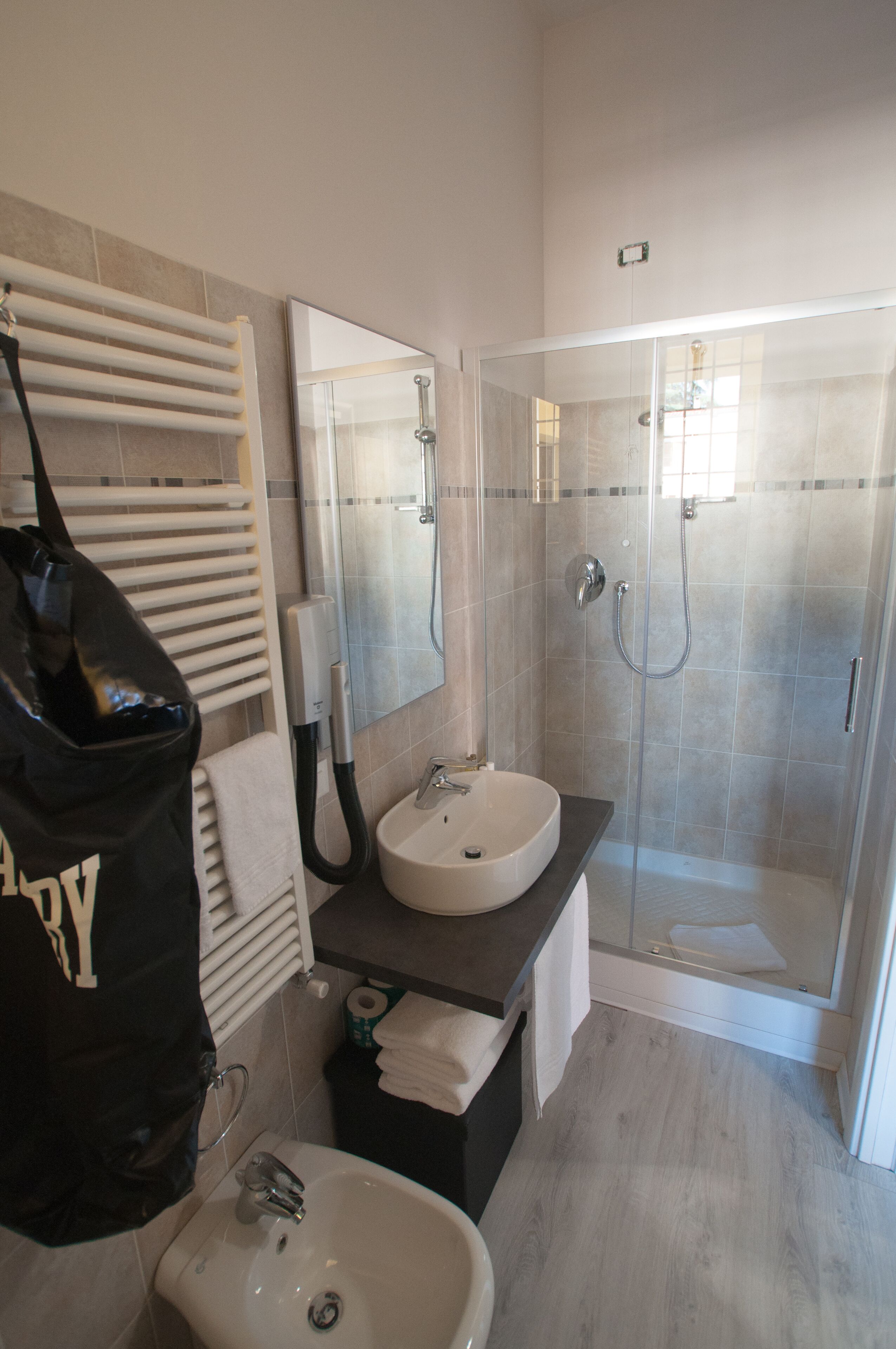 Uma casa de banho moderna com uma pia branca, um chuveiro com parede de vidro e um porta-toalhas.