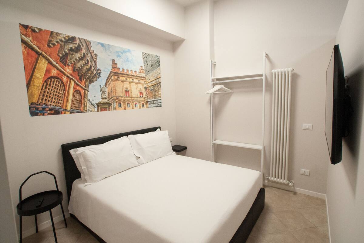 Ein Hotelzimmer mit Bett, Stuhl, Heizkörper und einem Bild an der Wand.