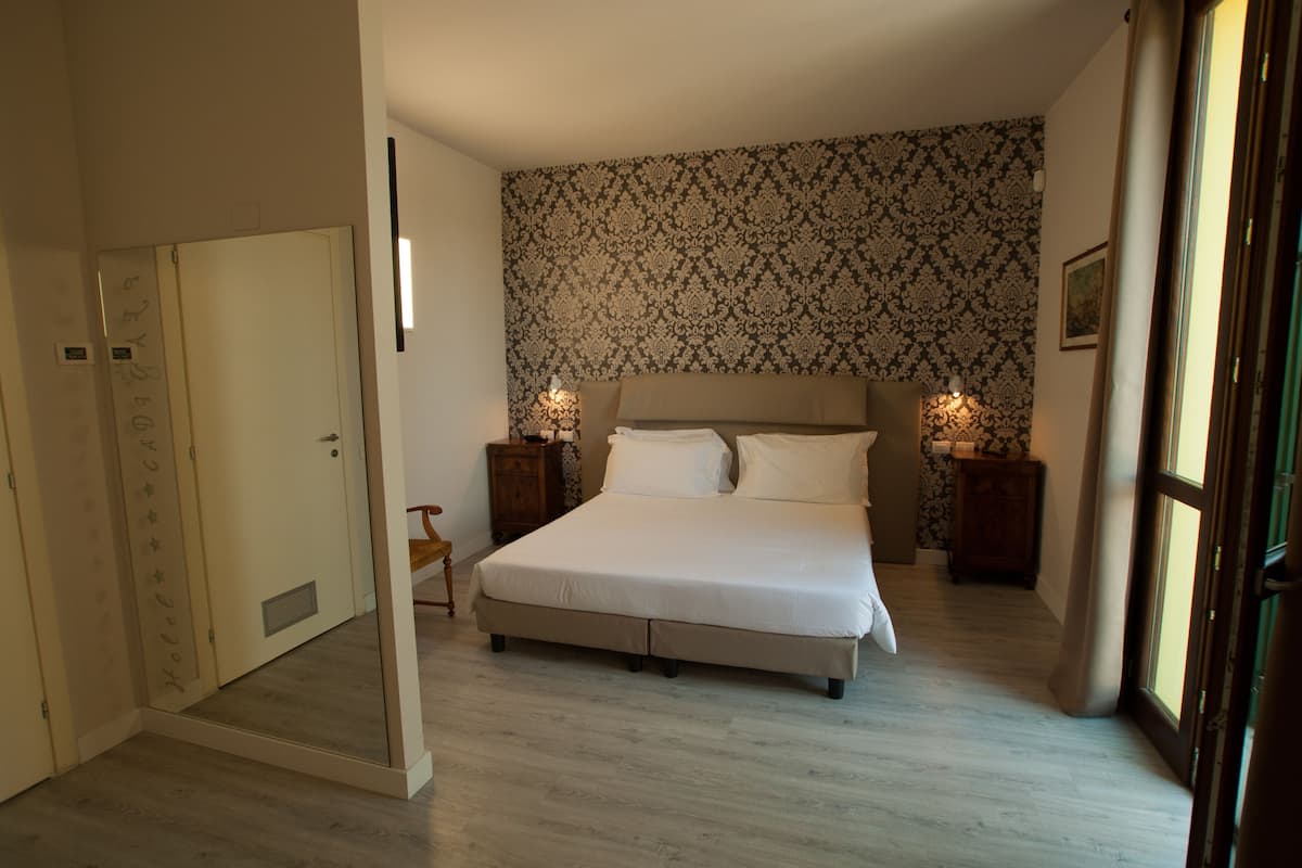 Ein Schlafzimmer mit Bett, Nachttischen, einem Spiegel und einer Wand mit Muster.