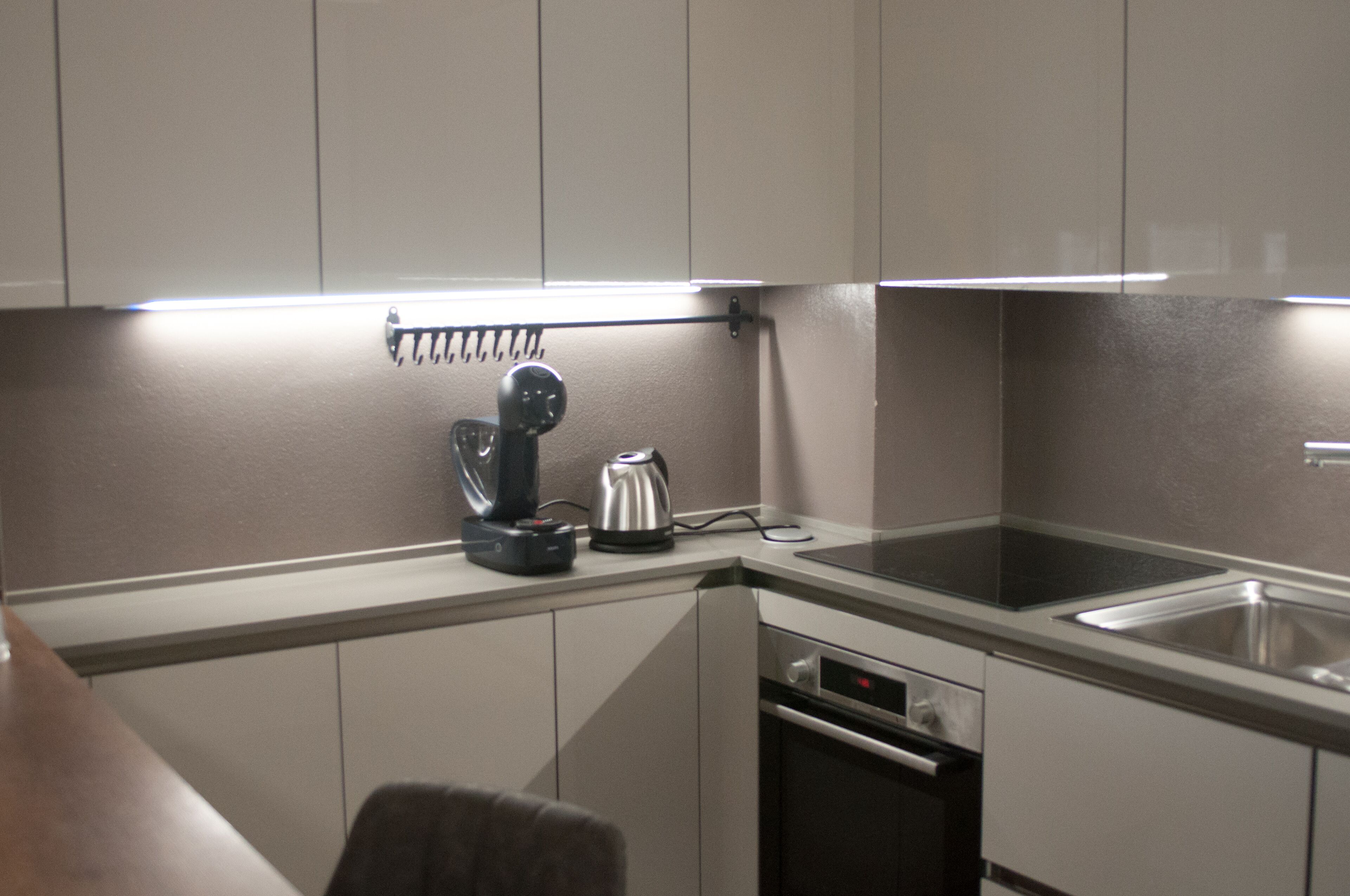 A modern kitchen with a built-in oven, a coffee maker, and a kettle on the countertop.