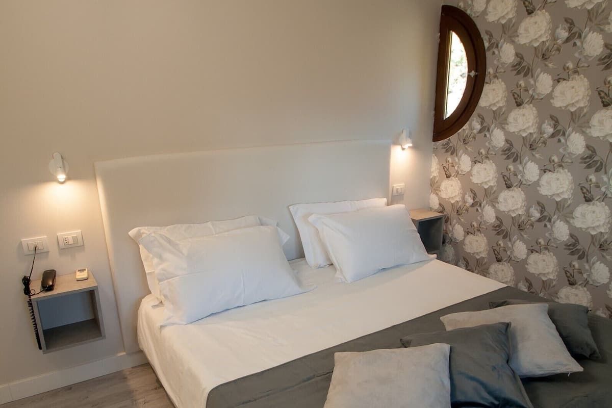Ein Schlafzimmer mit Bett, Nachttischen und blumigem Wandpapier.