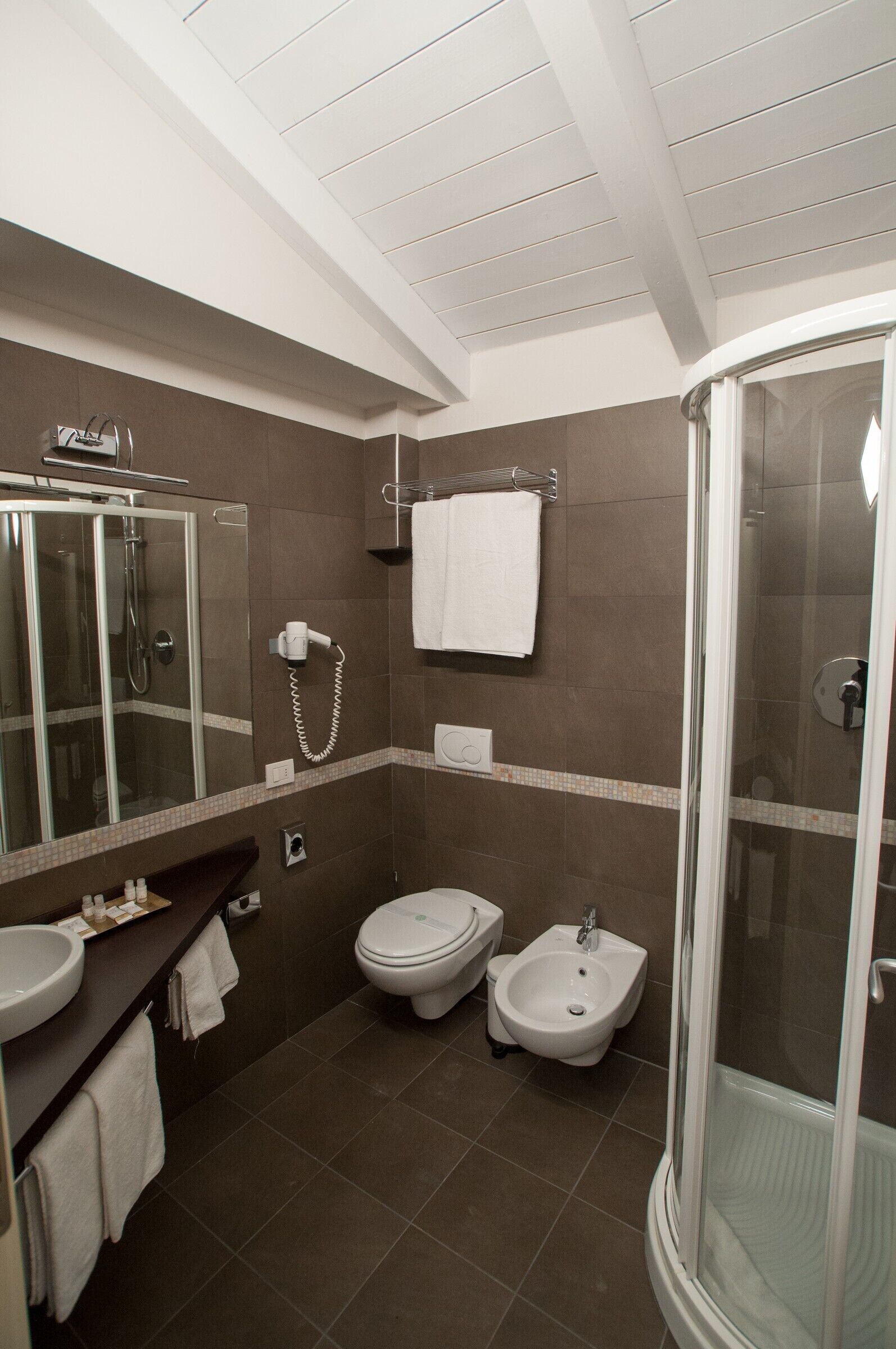 A modern bathroom with a glass-enclosed shower, a bidet, a toilet, and a sink.