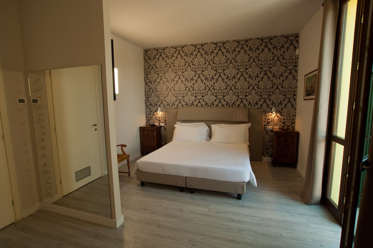 Ein Schlafzimmer mit einem Bett, Nachttischen, einem Kleiderschrank und raumhoch gestreifter Tapete.