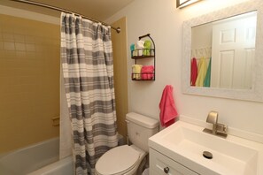 Ein Badezimmer mit Duschvorhang, Toilette, Waschbecken und Handtuchhalter.