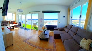 A spacious living room with a large sofa, a coffee table, and a TV mounted on the wall. There is a balcony with a view of the ocean. - Villa Vista Mar II, 280sqm Luxus, HotTube, amazing stunning oecan view, pool (Güime)