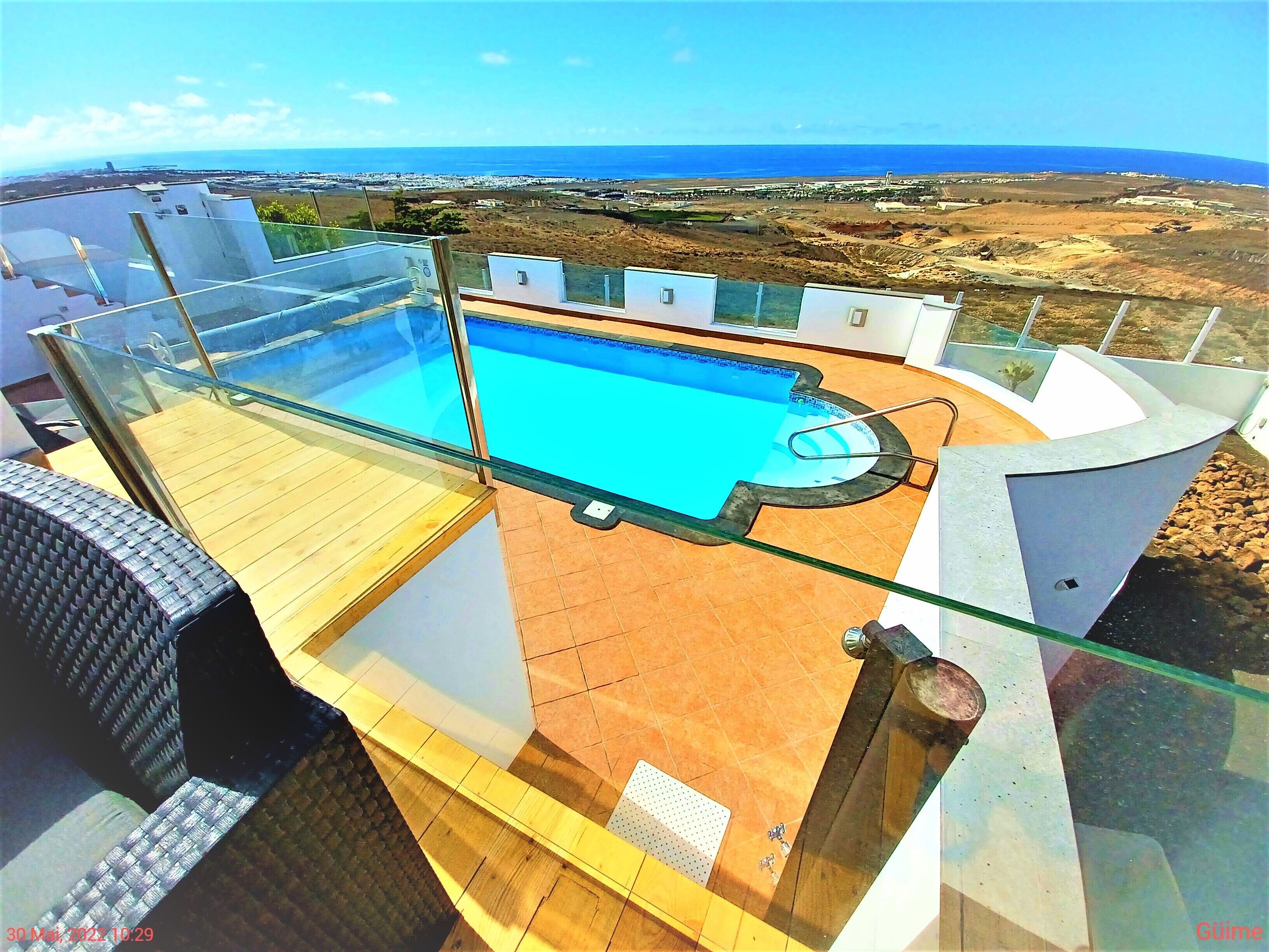 A rooftop pool with a clear view of the ocean and distant landscape.
