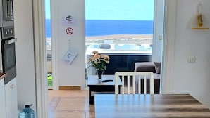 A modern kitchen with a built-in oven and a water dispenser. A dining area with a wooden table and white chairs is visible, leading to a balcony with a view of the sea. - Villa Vista Mar II, 280sqm Luxus, HotTube, amazing stunning oecan view, pool (Güime)
