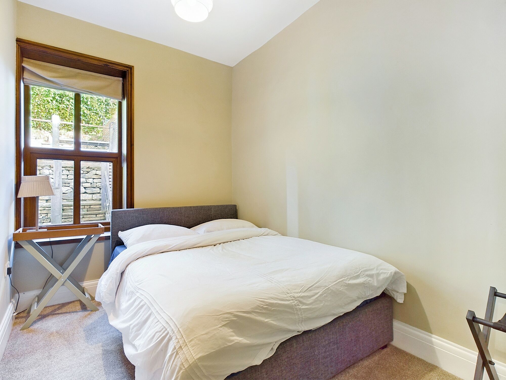 Un dormitorio con una cama, una ventana que da a zonas verdes y una silla.