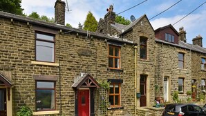 A stone building with a red door, windows, and a car parked in front. - Stoneswood Cottage, Delph, Saddleworth (Delph)