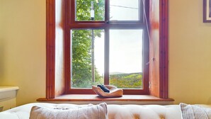 A bedroom with a large window, a wooden bed frame, and a view of greenery outside. - Stoneswood Cottage, Delph, Saddleworth (Delph)