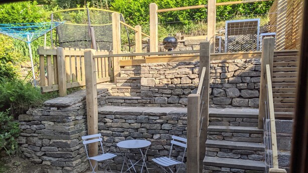 A stone staircase leading to a deck area with a grill and a hanging blue net. - Stoneswood Cottage, Delph, Saddleworth (Delph)