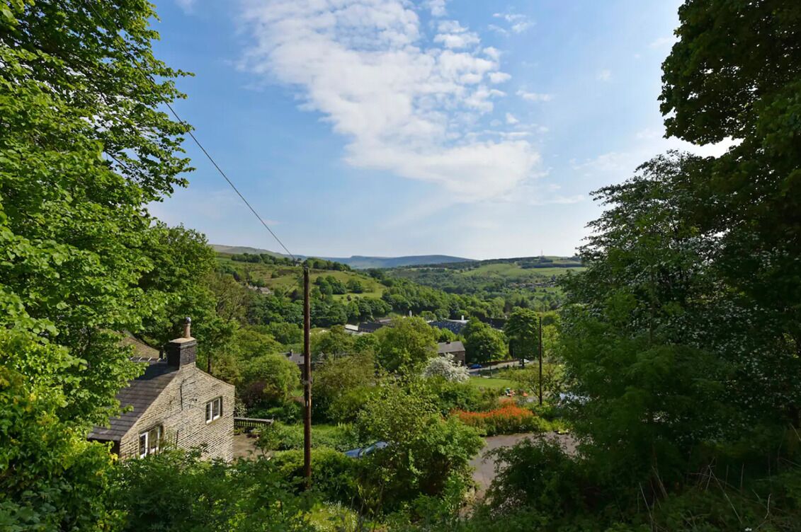 A stone house surrounded by lush greenery and a valley.