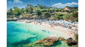 Une plage avec une eau turquoise et limpide, des chaises longues et des parasols.