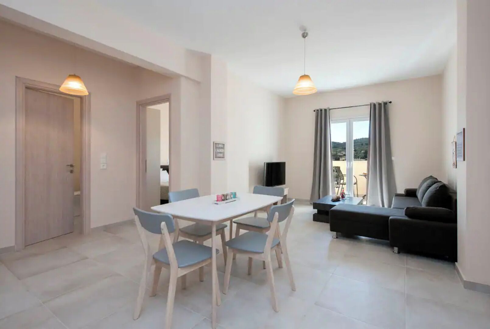 A modern living room with a dining area, a sofa, and a TV.