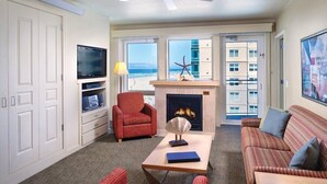 Ein Wohnzimmer mit Kamin, Fernseher und Blick auf den Strand.