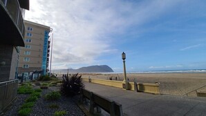 Ein Küstenweg mit einer Bank, einem Laternenpfahl und Blick auf Strand und Meer.