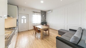 Eine moderne Küche mit Essbereich, einem grauen Sofa und einem Fernseher.