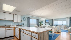 Una cocina moderna con armarios blancos, una isla central y un área de comedor con un tapete azul.