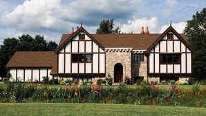 Een huis in Tudor-stijl met een entree onder een stenen bogenpoort, een grote tuin met kleurrijke bloemen en een helderblauwe lucht.