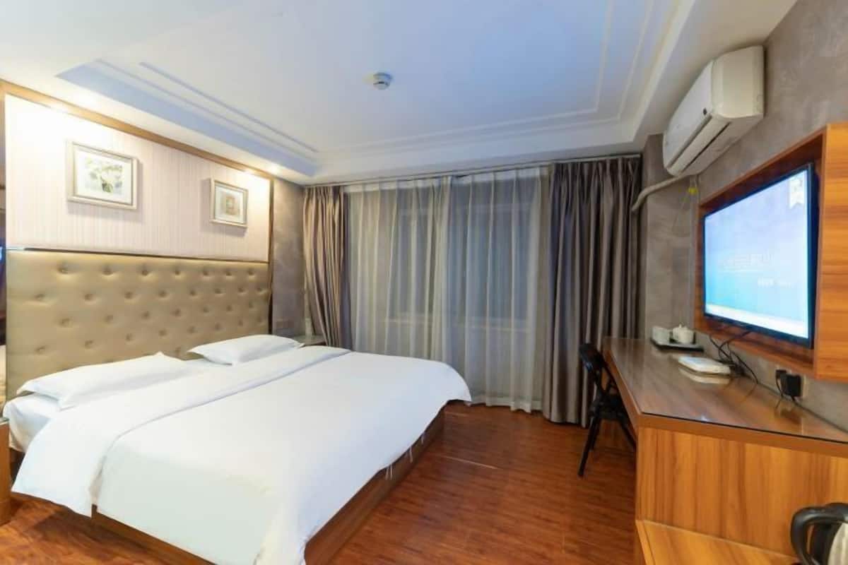 Une chambre d’hôtel avec un grand lit, un bureau avec un ordinateur et une télévision.
