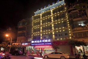 A hotel with multiple floors, illuminated windows, and a sign indicating it is the Tian Yuan Shangwu Jiu Dian hotel. - Tianyuan Business Hotel (Baise)