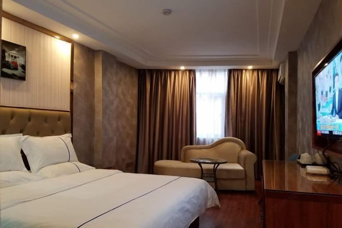 Une chambre d’hôtel avec un grand lit, un canapé, une petite table et un téléviseur.