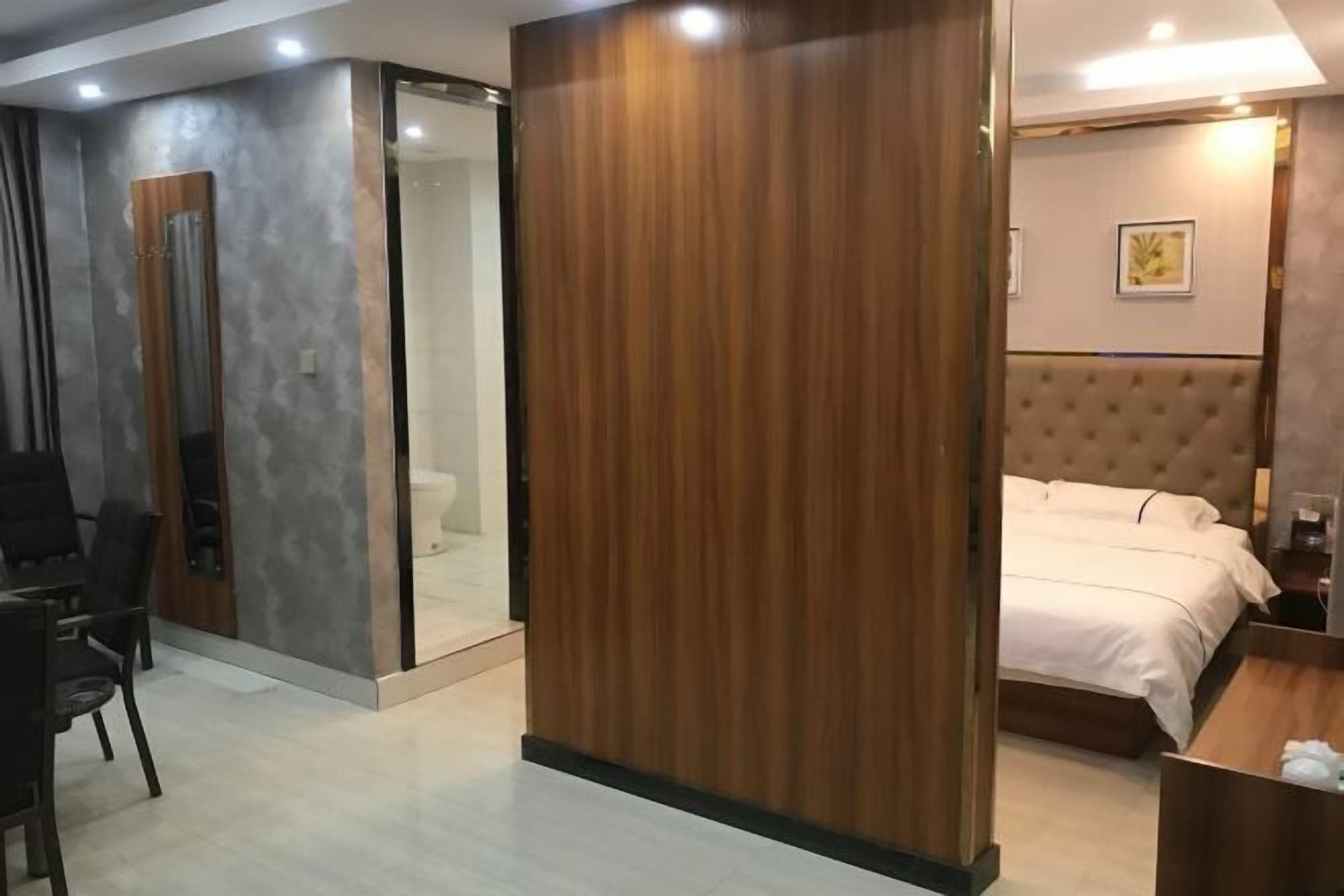 A hotel room with a bed, a desk, a chair, a wardrobe, and a bathroom.