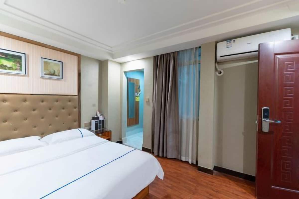 Une chambre d’hôtel avec un grand lit, une armoire, un appareil de climatisation et une porte dotée d’une poignée.