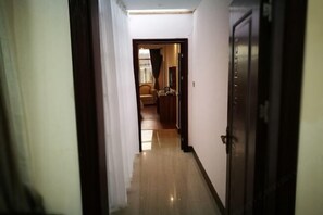 A hallway leading to a room with a wooden floor and a door on the right. - Tianyuan Business Hotel (Baise)