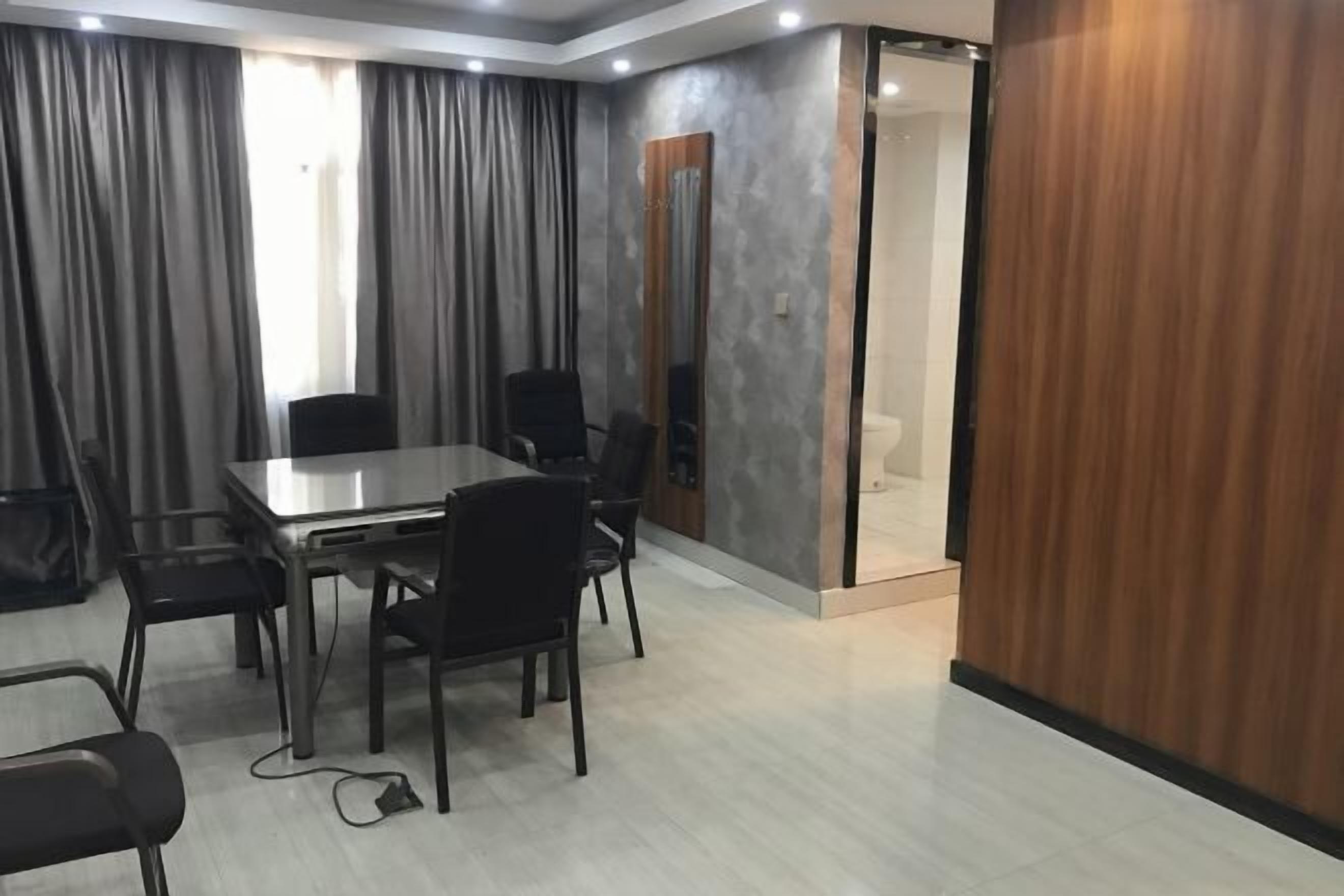 Uma sala de conferências com uma mesa retangular, seis cadeiras e um espelho grande na parede.