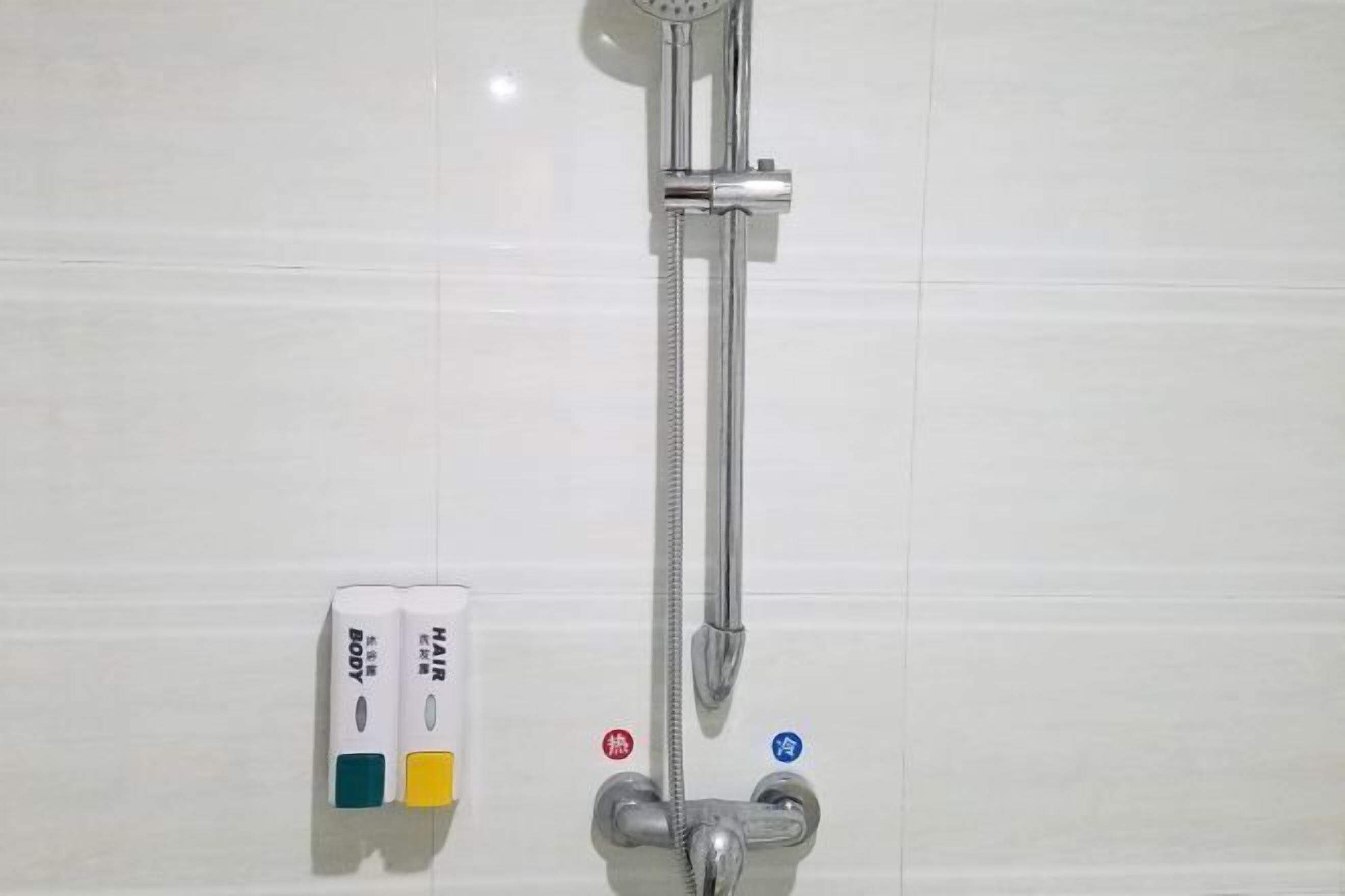 A bathroom with a shower, a towel rack, and a soap dispenser.