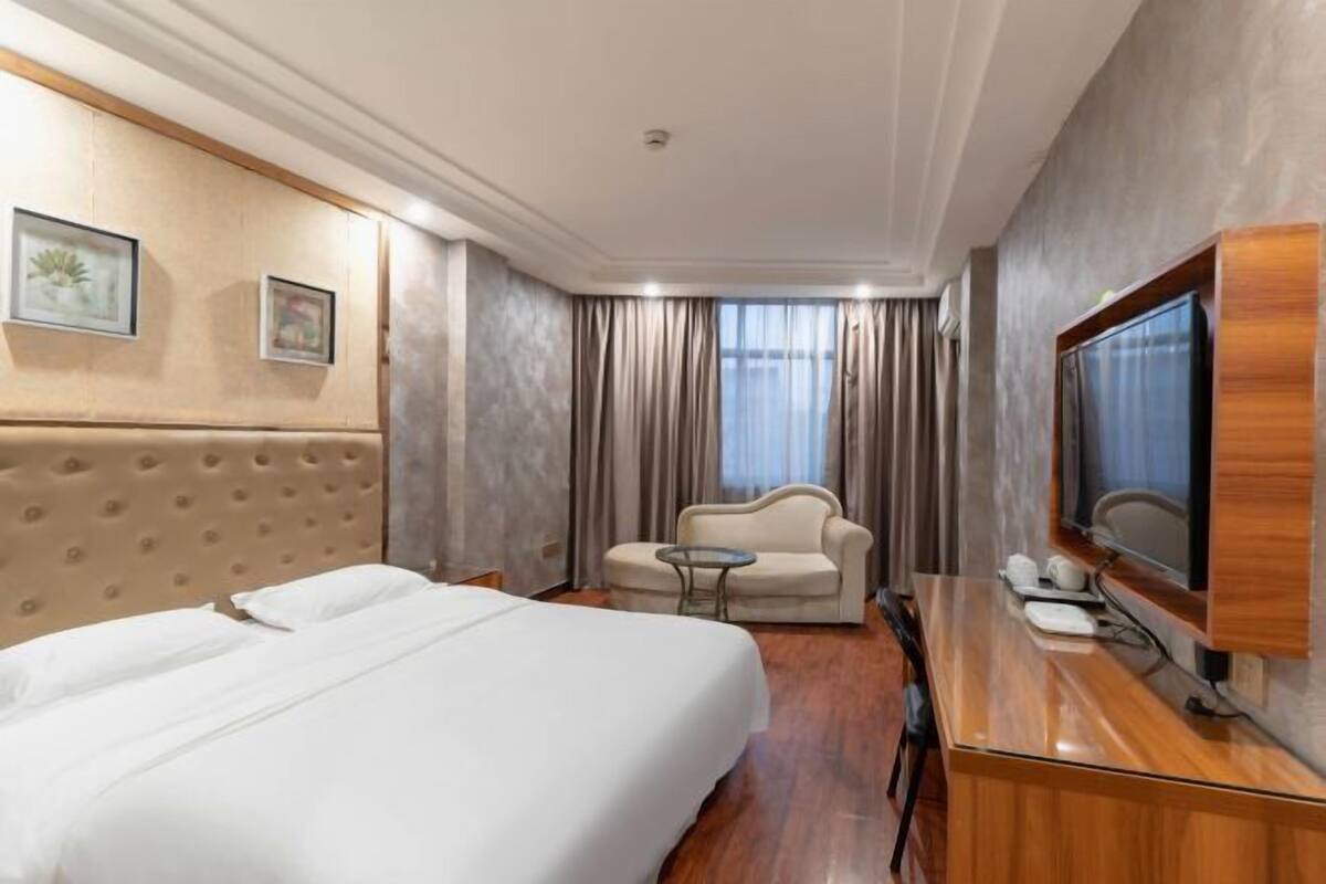 Une chambre d’hôtel avec un lit, un canapé, une télévision et un bureau.