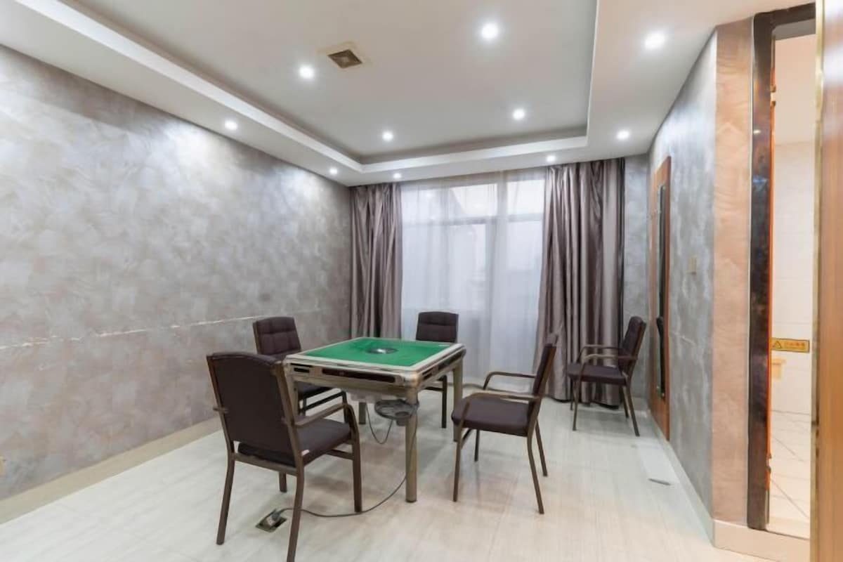 A room with a pool table, four chairs, a ceiling light fixture, and a door with a sign.