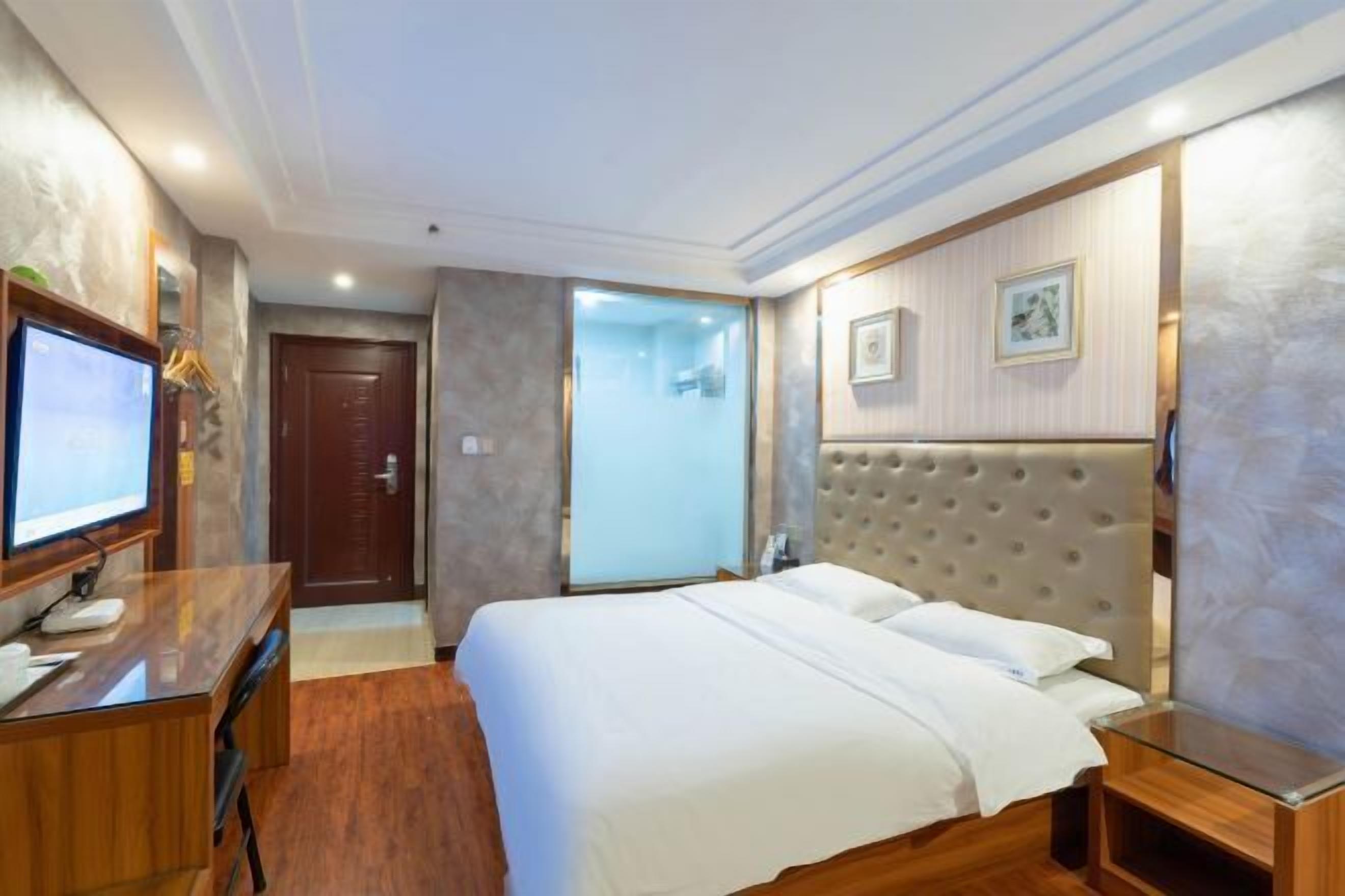 Une chambre d’hôtel comprenant un lit, un bureau, une télévision et une porte donnant accès à une salle de bain.