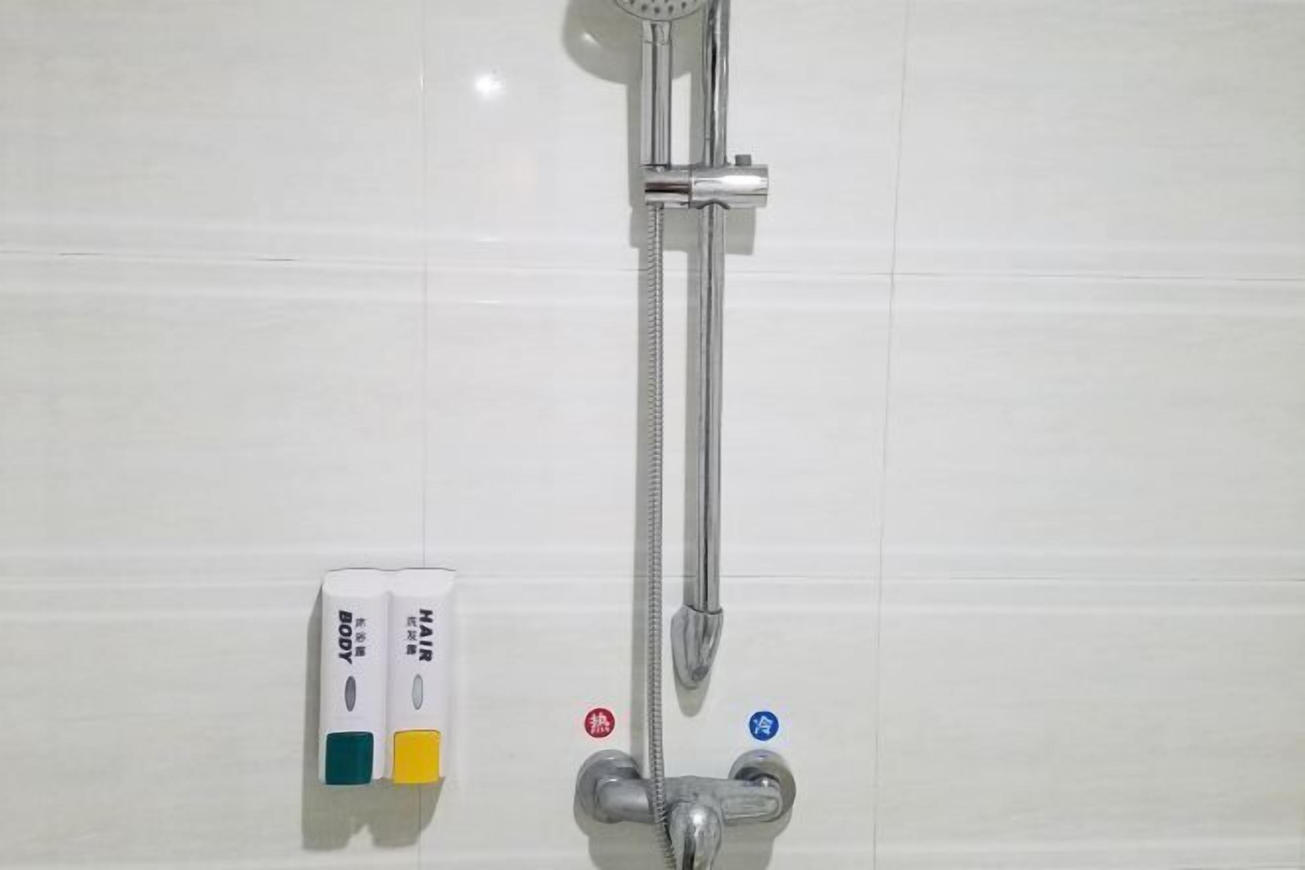 A shower with a handheld showerhead and a wall-mounted control panel with temperature and water flow settings.