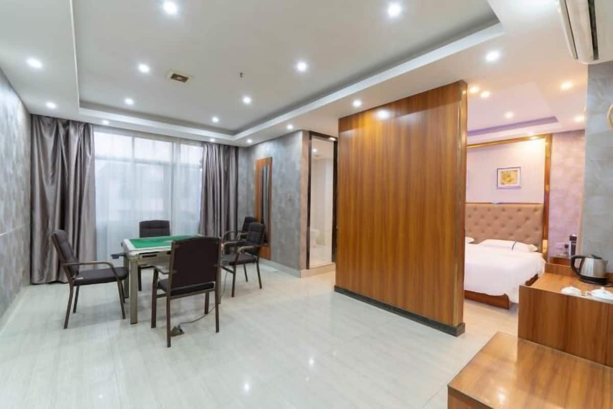 Une chambre d’hôtel comprenant un lit, un bureau avec des chaises, une table de billard et une cloison en bois.