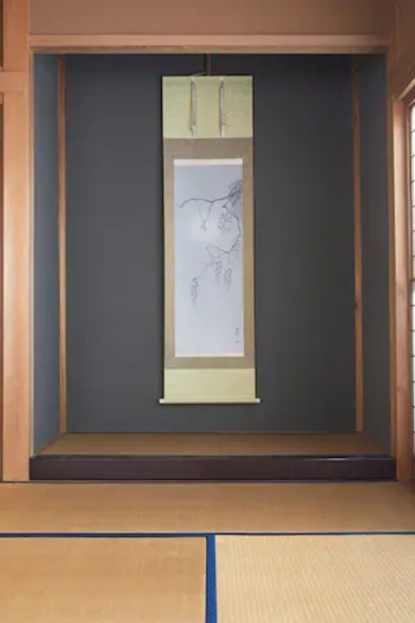 Ein traditioneller japanischer Raum mit Tatami-Boden, Shoji-Schirm und einer aufgehängten Schriftrolle.