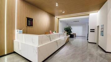Un'area reception con un bancone in marmo, un soffitto in legno e una pianta sullo sfondo.