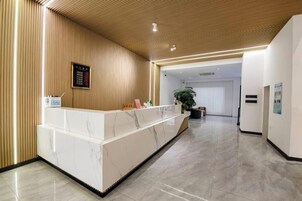 Un área de recepción con mostrador de mármol, techo de madera y una planta al fondo.