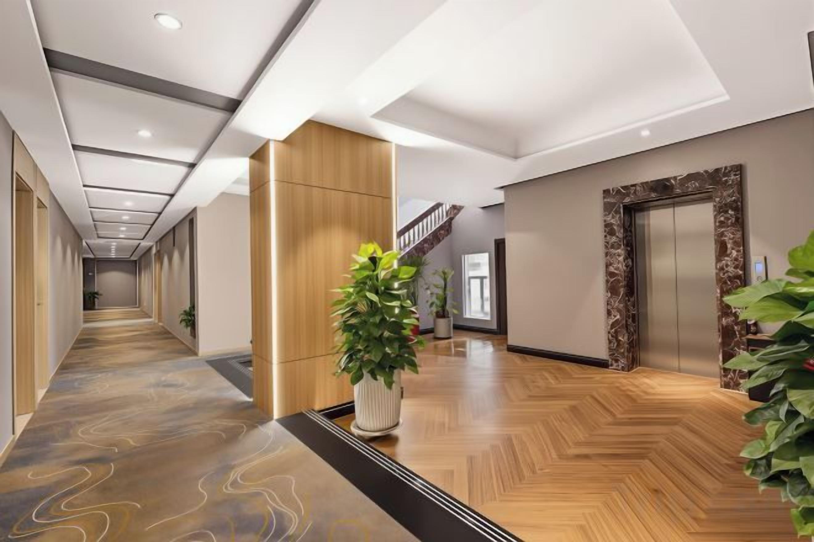 Un vestíbulo de hotel con piso de madera, una recepción, una escalera y un ascensor.