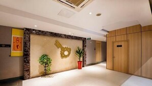 En hotellobby med en reception af marmor, en trädør og en potteplante.