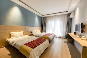 Habitación de hotel con dos camas, un escritorio, un televisor y un ventanal con cortinas.