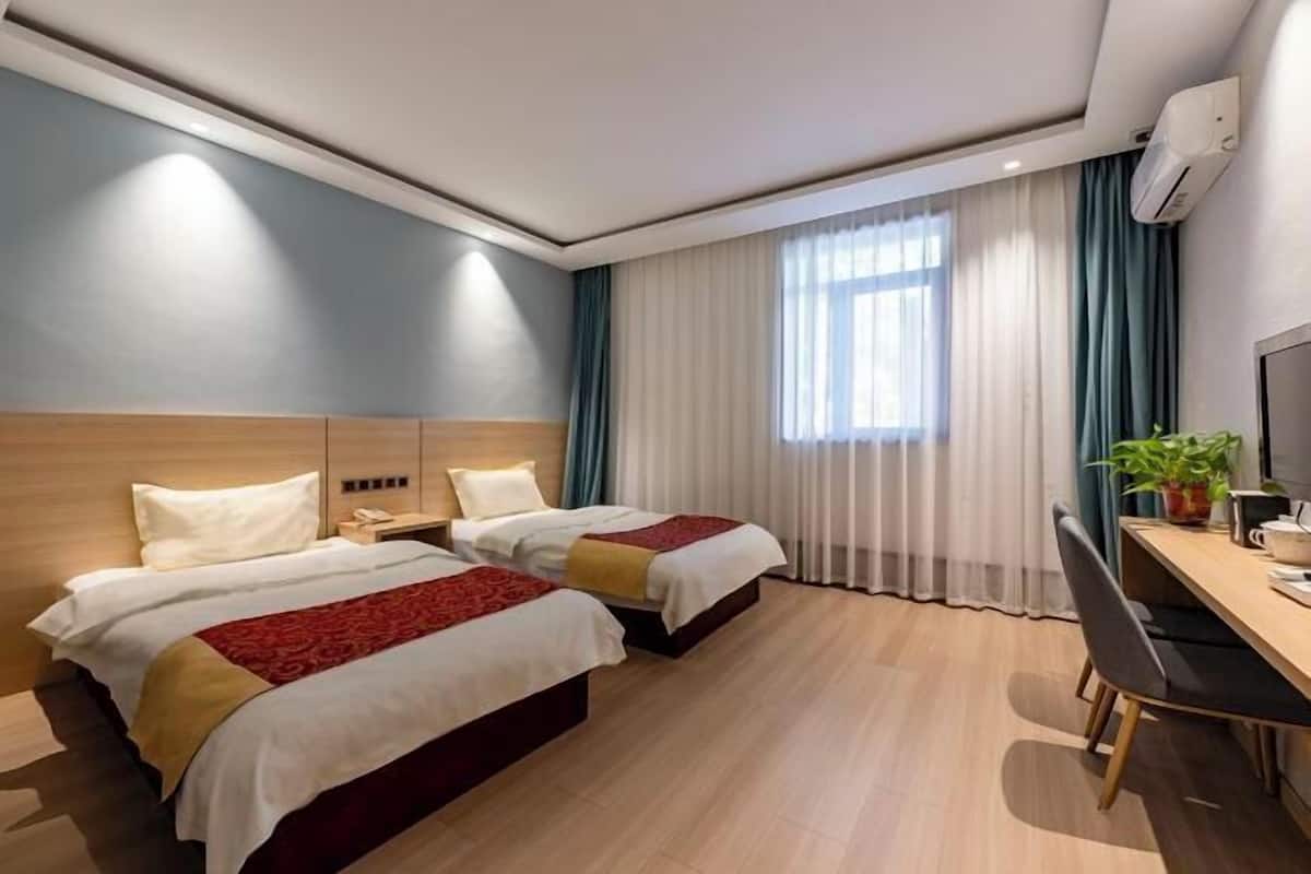Quarto de hotel com duas camas, uma escrivaninha e uma cadeira.