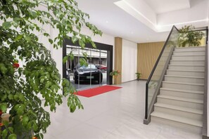 Un intérieur moderne avec un escalier, une moquette rouge et une voiture en arrière-plan.