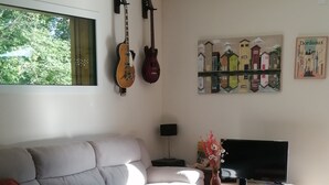 Una sala de estar con un sofá, una mesa de centro, un televisor y guitarras en la pared.