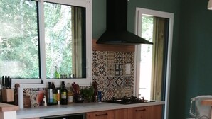Una cocina con armarios de madera, horno empotrado y ventana con vistas a árboles.