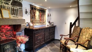 A cozy room with a stone fireplace, a wooden cabinet, and a floral armchair. - Medieval Getaway (Fougères)