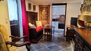 A cozy living area with a sofa, a dining table, and a kitchen in the background. - Medieval Getaway (Fougères)