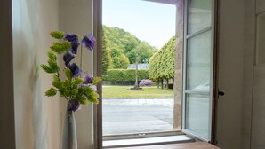 A room with a wooden bench and a vase of purple flowers on a windowsill. - Medieval Getaway (Fougères)