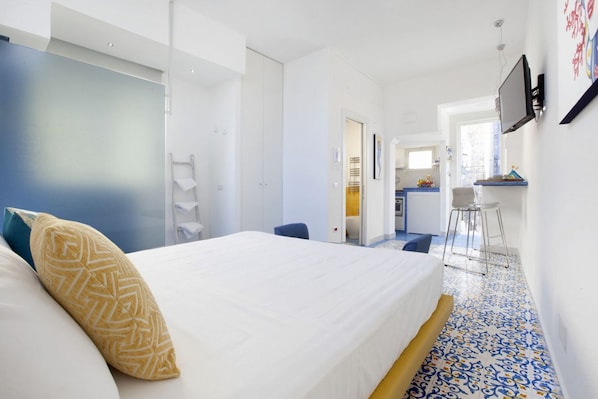 A hotel room with a bed, a desk, a chair, and a TV.